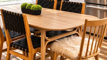 Une table de salle à manger en bois, accompagnée de quatre chaises, chacune dotée d’un siège et d’un dossier rembourrés de couleur noire.