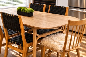 A wooden dining table with four chairs, each with a black cushioned seat and backrest.
