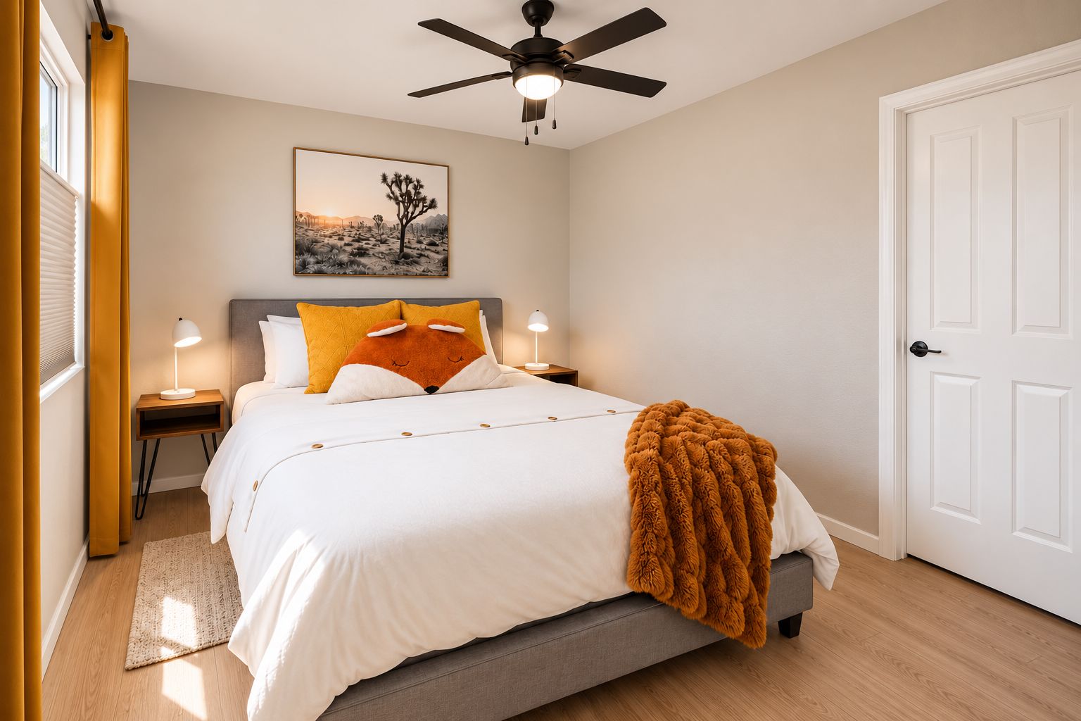 A bedroom with a bed, a ceiling fan, a nightstand with a lamp, a door, and a window with blinds.