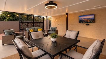 Una terrazza esterna con tavolo, sedie e un vaso di fiori.