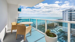 A balcony with wicker chairs and a table, overlooking a beach and cityscape. - Luxurious 1/1 Ocean View Condo 1416 - Located at 1 Hotel & Homes South Beach (Miami Beach)