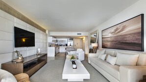 A modern living room with a flat-screen TV, a large painting, and a sofa. - Luxurious 1/1 Ocean View Condo 1416 - Located at 1 Hotel & Homes South Beach (Miami Beach)
