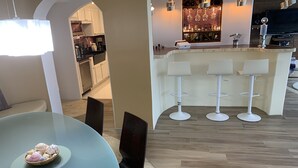 Una cocina moderna con armarios blancos, una encimera negra y una zona de bar con taburetes blancos.