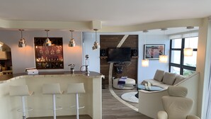 Una sala de estar moderna con una zona de bar, un espacio de descanso acogedor y una televisión.
