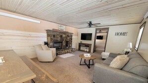 Una sala de estar acogedora con chimenea de piedra, un sofá, una mesa de centro y un televisor.