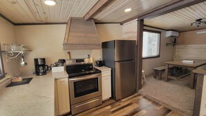 Una cocina compacta equipada con horno, refrigerador de acero inoxidable y cafetera.