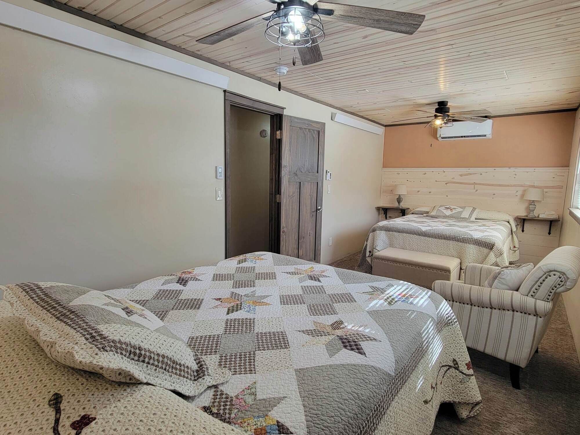 A bedroom with a bed, a chair, a wardrobe, and a ceiling fan.