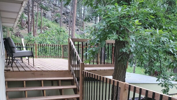 Una terraza de madera con una silla y una escalera que lleva a un área cubierta.
