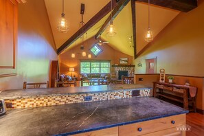 A spacious kitchen with a large island, a stone fireplace, and a dining area with wooden furniture. - Mountain Run  | 4 Bed, 3 Bath (Wilmington)