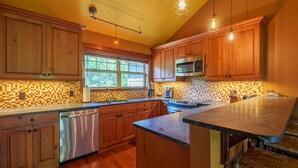 Una cocina con armarios de madera, lavavajillas de acero inoxidable, microondas y una isla grande con un fregadero.
