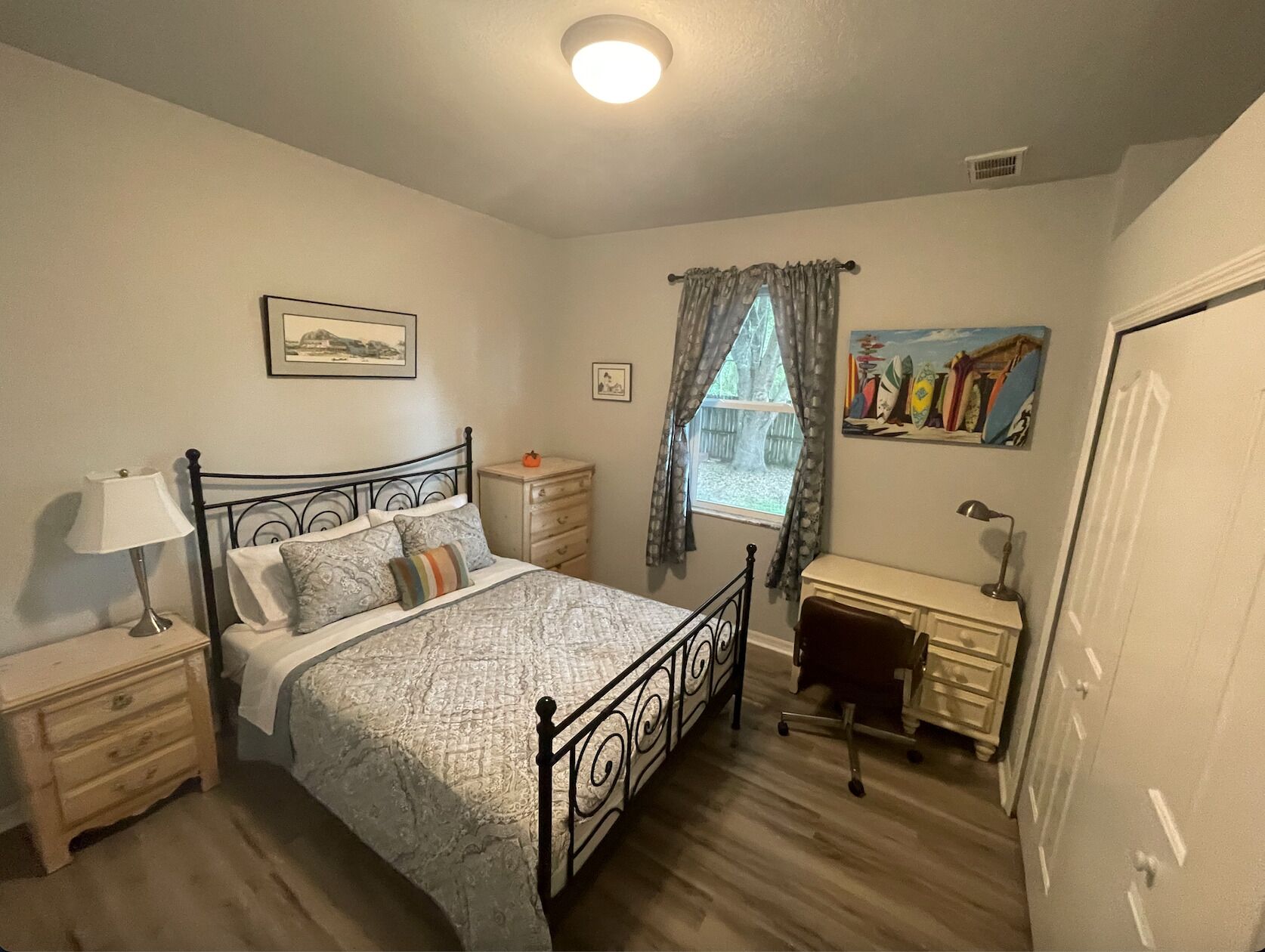 A bedroom with a bed, nightstands, a desk, and a chair.