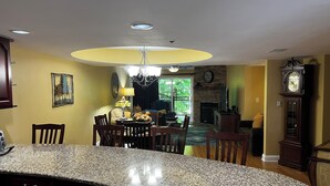 Uma cozinha com bancadas de granito, cadeiras de madeira, uma mesa de jantar, um candelabro e uma lareira.