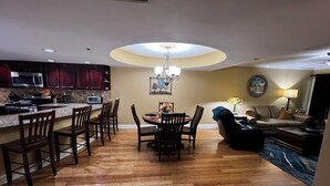 Cozinha moderna com área de refeições, piso de madeira e luminária no teto.