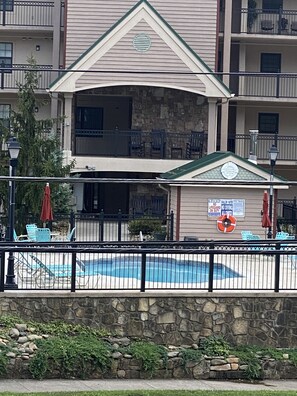 A multi-story building with a pool area, stone walls, and outdoor furniture. - CREEKSIDE VIBES 2BR/2BA 1ST FLOOR, WALK TO GATLINBURG, -AUGUST SPECIAL! BOOK NOW (Gatlinburg)