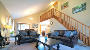 A spacious living room with two leather sofas, a coffee table, and a staircase leading to an upper level.