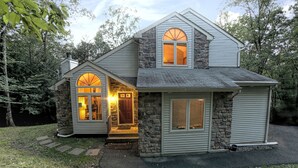 A two-story house with a stone facade, large windows, and a front porch.