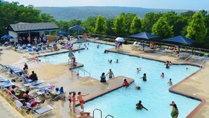 A swimming pool area with multiple pools, sun loungers, and umbrellas.