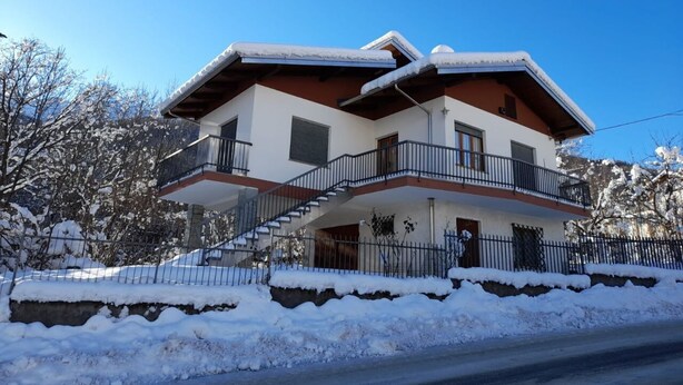 Ein zweistöckiges Haus mit Balkon, umgeben von Schnee.