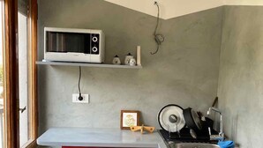 Eine kleine Küche mit Mikrowelle, Spüle und einem kleinen Fenster.