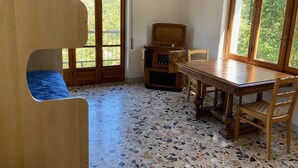 Ein Zimmer mit Holztisch und -stühlen, einer blauen gepolsterten Bank, einem Plattenspieler und einem gefliesten Boden.