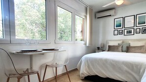 A bedroom with a bed, a dining table with chairs, and a window with a view of trees. - Wonderful Studio in Marbella Centre on the Second Line Beach (Marbella)