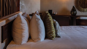A hotel room with a bed, pillows, a remote control, a wall-mounted mirror, and hanging pendant lights. - Nerea Tulum (Tulum)