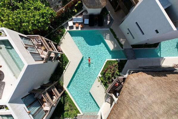 A resort with a central swimming pool, multiple balconies, and lush greenery.