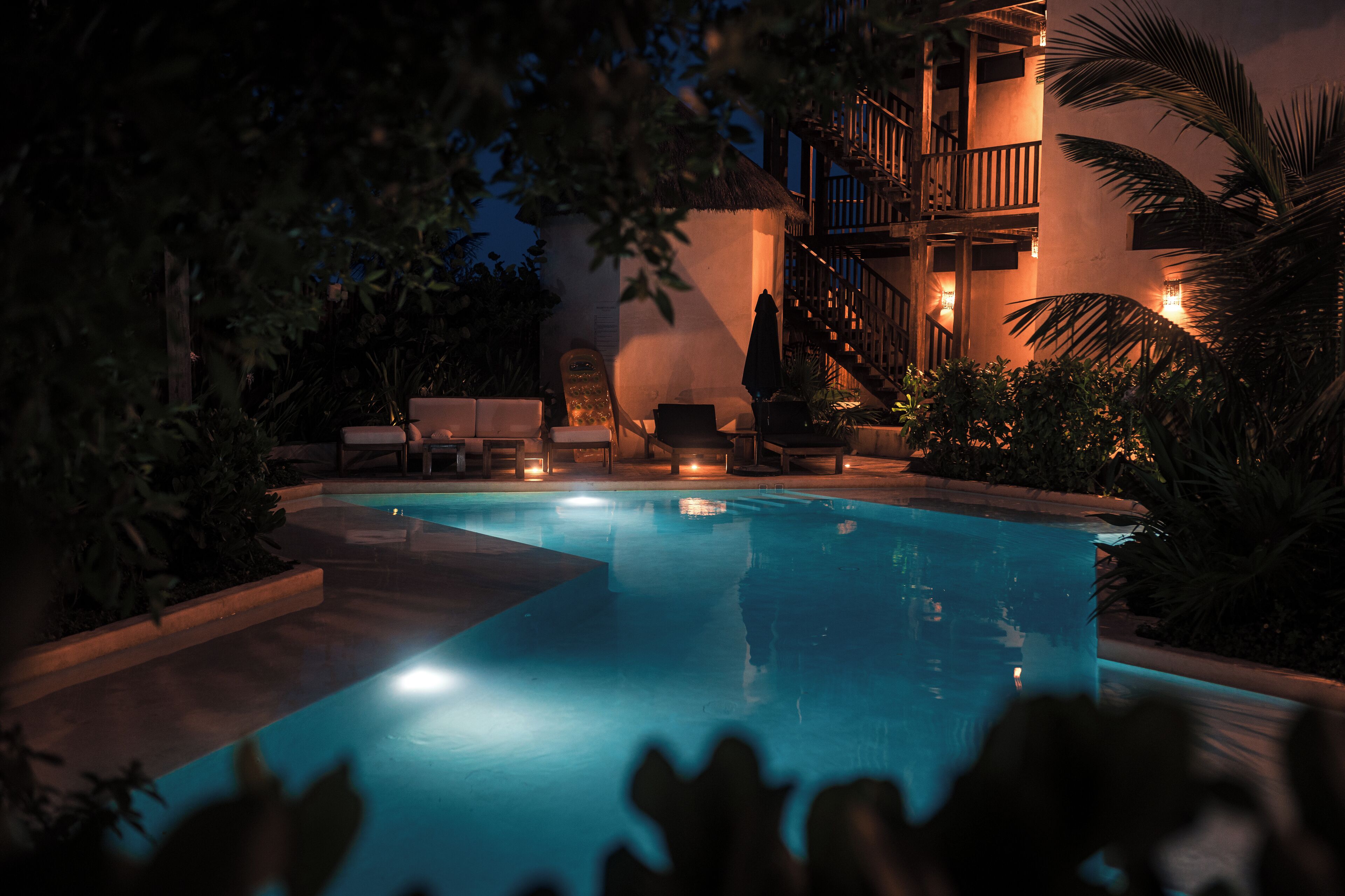 A swimming pool with lounge chairs and a staircase leading to an upper level.