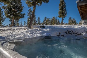 A hot tub in a snowy outdoor setting with trees in the background.