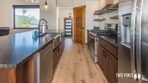 Een moderne keuken met een groot eiland, roestvrijstalen apparatuur en houten keukenkastjes.