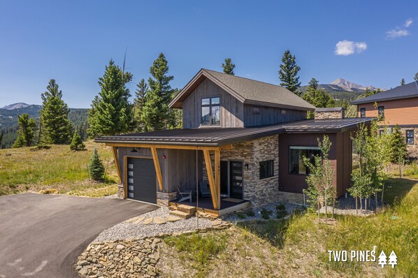 A modern two-story house with a stone facade, large windows, and a covered porch.