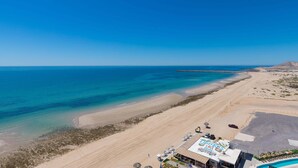 A beachside hotel with a pool, beach access, and a clear view of the ocean.