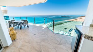 A balcony with a view of the ocean, a dining area with chairs, and a large vase.