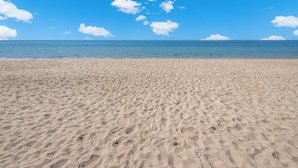 A sandy beach with footprints leading to the water. - Esmeralda Beach Resort 2 Bedrooms Condo A 203 (Puerto Peñasco)