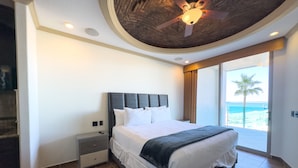 A hotel room with a bed, nightstand, and a view of the beach. - Esmeralda Beach Resort 2 Bedrooms Condo A 203 (Puerto Peñasco)