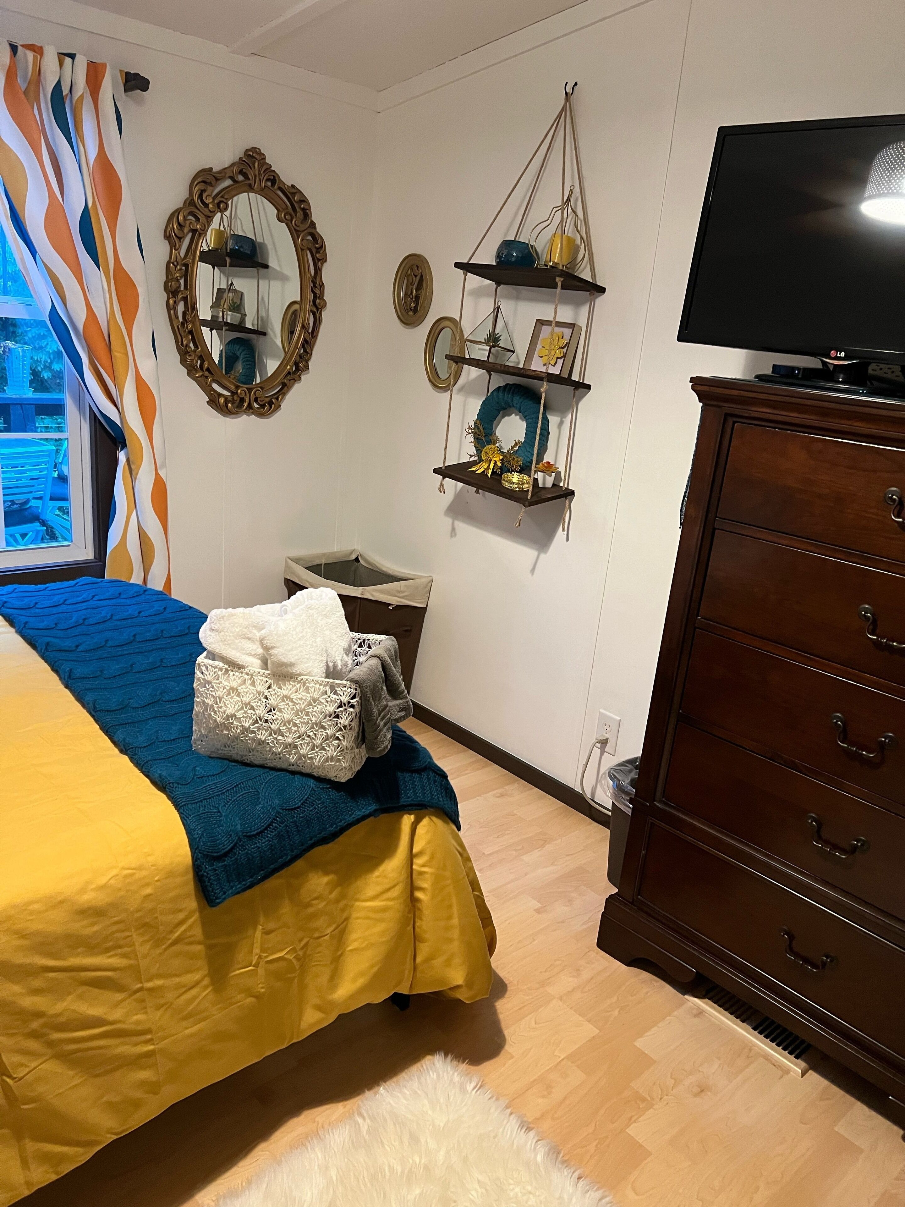 Une chambre à coucher comprenant un lit, une commode, un téléviseur et des étagères décoratives.