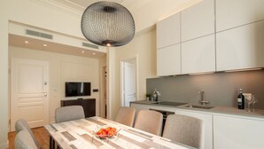 A modern kitchen with a dining area, a TV, and a large pendant light. - Florence Luxury Apartment al Duomo by Mmega (Firenze)