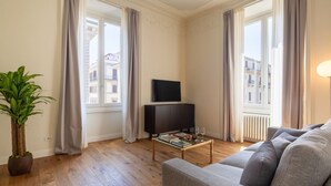 A living room with a sofa, a coffee table, a TV, and a potted plant. - Florence Luxury Apartment al Duomo by Mmega (Firenze)
