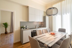 A modern kitchen with a dining area, a potted plant, and a hanging light fixture.