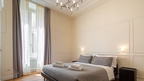 A bedroom with a large bed, a chandelier, and a radiator. - Florence Luxury Apartment al Duomo by Mmega (Firenze)