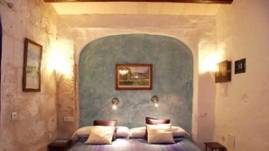 A bedroom with a single bed, a framed picture on the wall, and two wall-mounted lights. - Matchani Gran (Mahón)