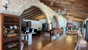 A spacious kitchen with wooden flooring, stone walls, and a long dining table. - Matchani Gran (Mahón)