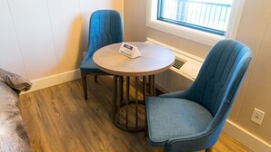 A room with a round wooden table, two blue upholstered chairs, a bed with a patterned blanket, and a window with a view of a balcony. - Stay Express Inn Chattanooga (Chattanooga)