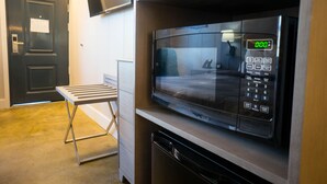 A microwave oven with a digital display, a small table, and a door in a room with a light-colored floor. - Stay Express Inn Chattanooga (Chattanooga)