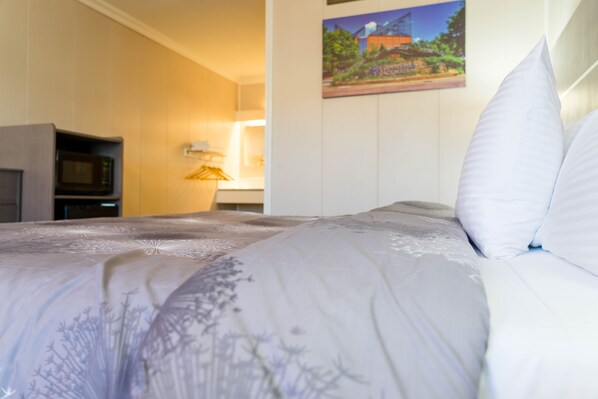 A hotel room with a bed, a television, and a painting on the wall.