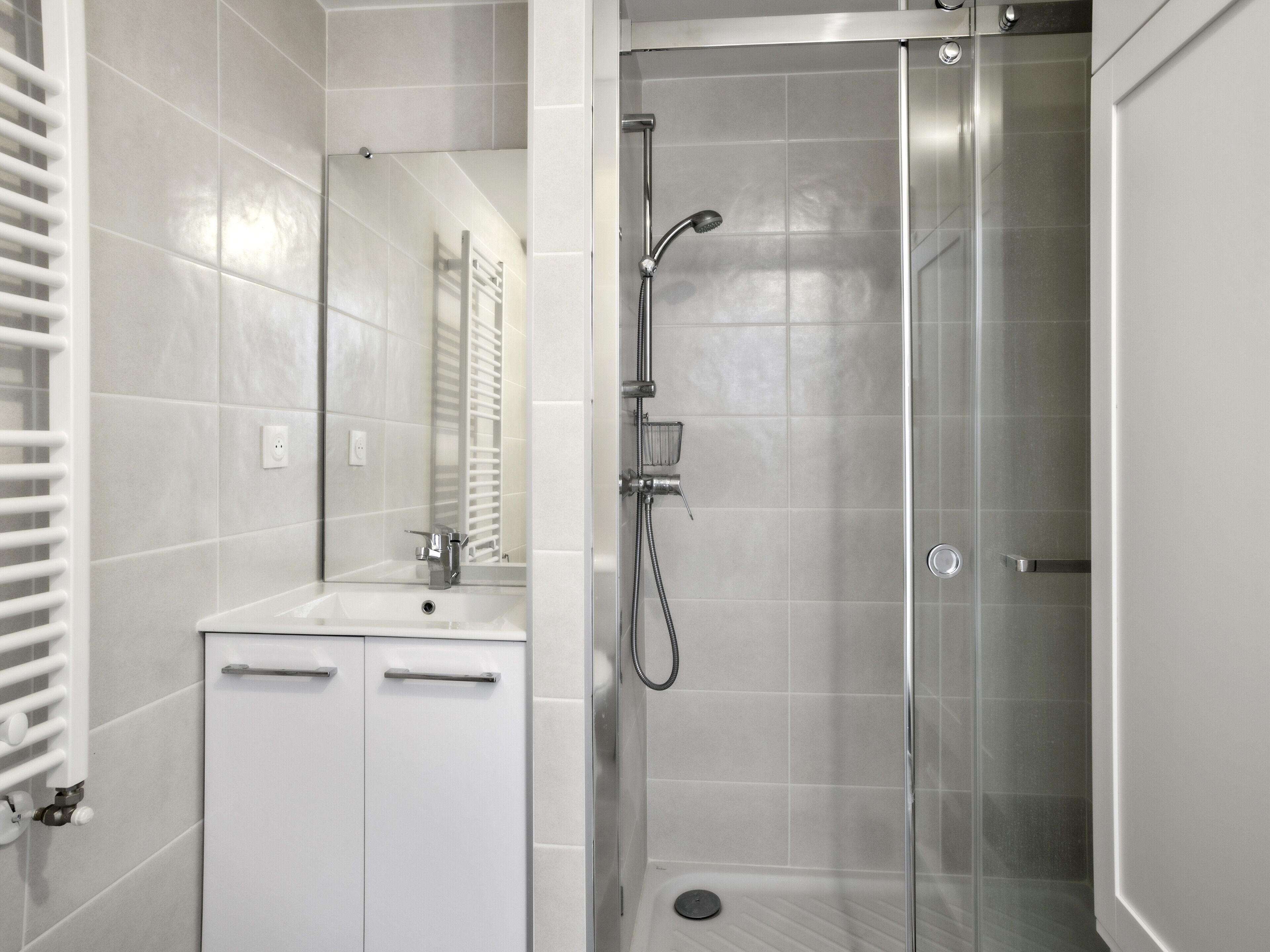 Ein modernes Badezimmer mit Dusche, Waschbecken und Spiegel.