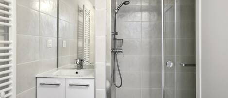 Ein modernes Badezimmer mit Dusche, Waschbecken und Spiegel.