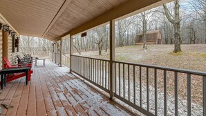 A covered porch with wooden flooring, a railing, and a view of a wooded area with a small building in the background. - 2 Mi to Elk Mountain: Poconos Escape on 11 Acres! (Union Dale)