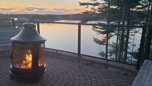 A fire feature on a rooftop patio overlooking a lake, with a view of trees and buildings in the distance. - Where Luxury and Tranquility Meet (Whitbourne)