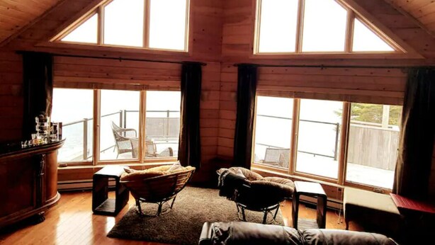 A cozy room with a sloped ceiling, large windows, a wooden floor, a chair, a sofa, and a small table. - Where Luxury and Tranquility Meet (Whitbourne)